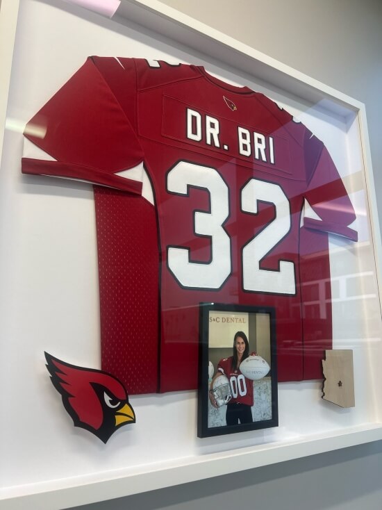 AZ Cardinals Jersey with a photo of dentist Dr. Bri wearing the jersey and holding a football and helmet