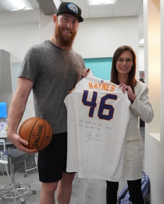 Dr. Bri standing next to Aaron Baynes while holding autographed #46 Phoenix Suns NBA jersey Scottsdale AZ