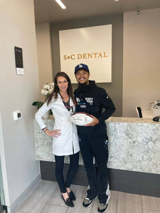 Dr Bri smiling next to patient holding football at S&C Dental Scottsdale AZ