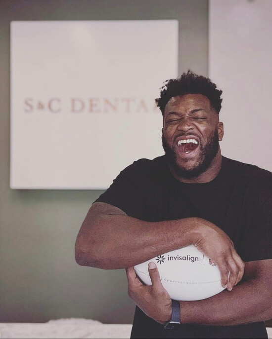 Football player with whitened teeth holding football at S&C Dental Scottsdale AZ