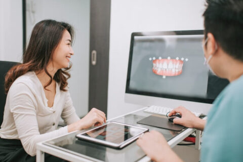 The Dentist explaining Dental Implants Vs. Veneers on computer to the patient at Scottsdale, AZ.