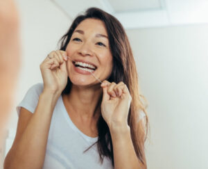 The Beautiful Woman flossing Her teeth at S&C dental in Scottsdale AZ.