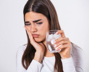 Female drinking ice water and having sensitive teeth